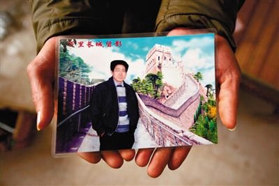 尹小枫的儿子捧着父亲相片。